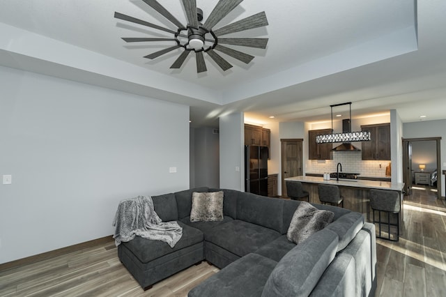 living area featuring wood finished floors, a ceiling fan, recessed lighting, and baseboards