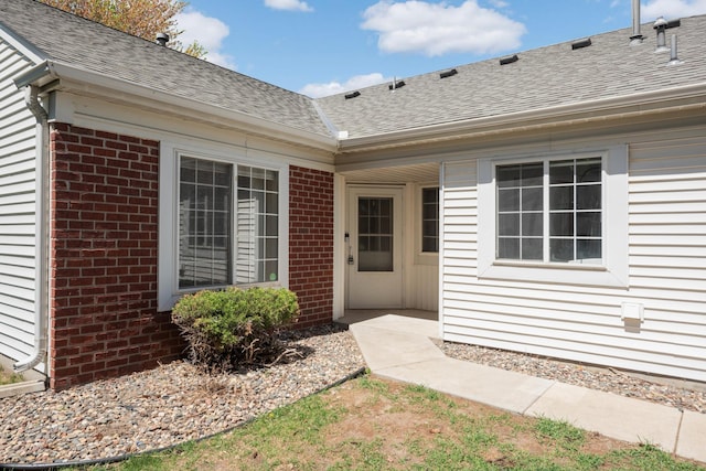 entrance to property with brick siding and roof with shingles