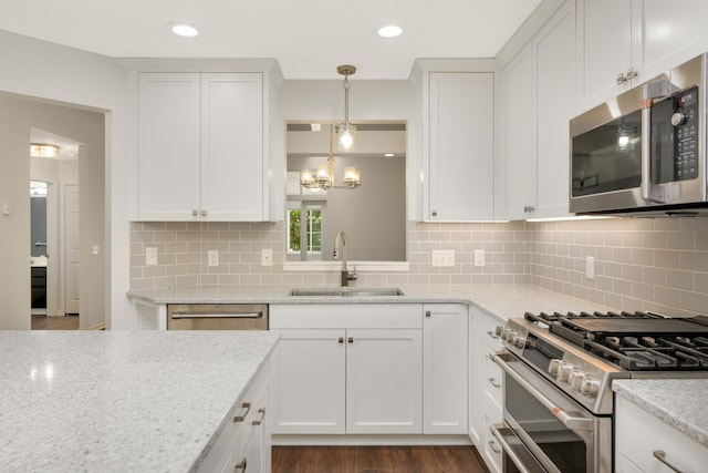 kitchen featuring appliances with stainless steel finishes, a sink, white cabinetry, tasteful backsplash, and recessed lighting