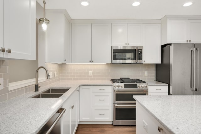 kitchen with appliances with stainless steel finishes, a sink, white cabinets, backsplash, and recessed lighting