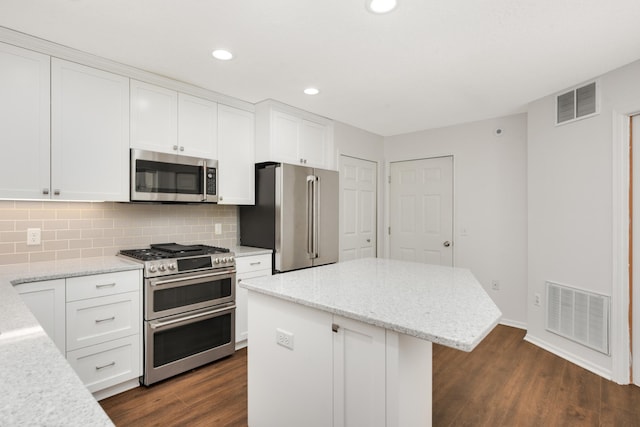 kitchen with stainless steel appliances, dark wood-style flooring, a kitchen island, tasteful backsplash, and white cabinets