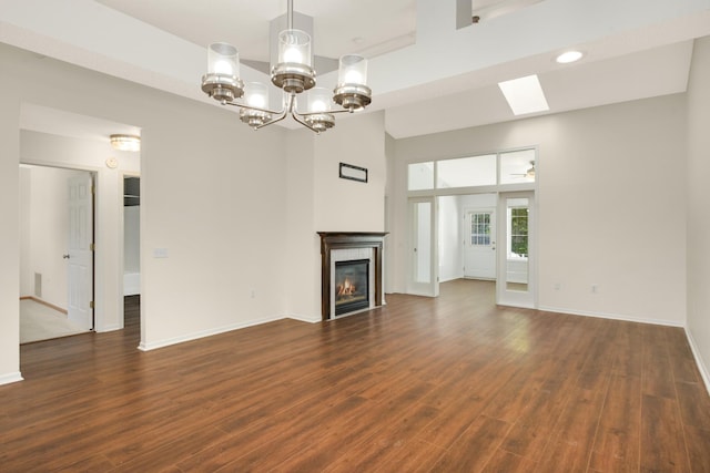 unfurnished living room with a fireplace, baseboards, dark wood-style floors, a chandelier, and recessed lighting