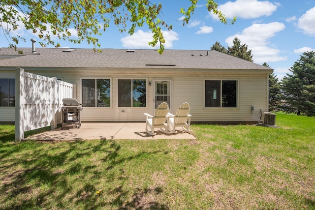 rear view of house with cooling unit, a patio, a lawn, and roof with shingles