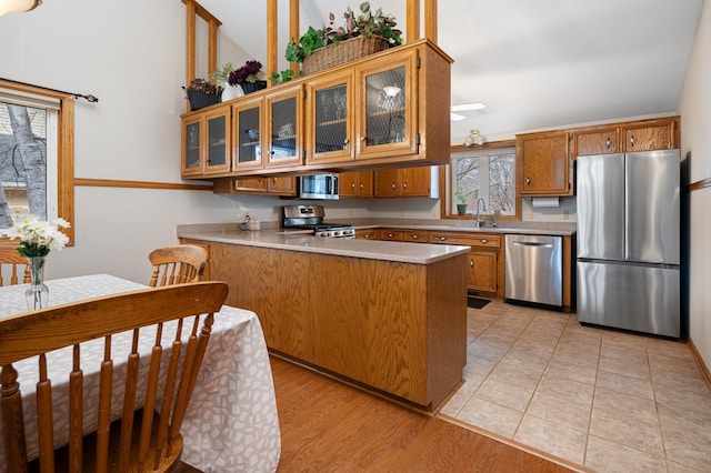 1944 Linda Ln, Saint Cloud, MN 56301 - kitchen with appliances with stainless steel finishes, a peninsula, brown cabinets, light countertops, and glass insert cabinets