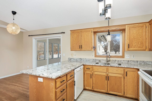 kitchen with pendant lighting, light wood-style flooring, a sink, white appliances, and a peninsula