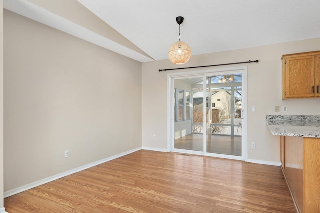 unfurnished dining area featuring lofted ceiling, light wood-style floors, baseboards, and visible vents