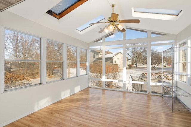 unfurnished sunroom featuring vaulted ceiling with skylight and a ceiling fan