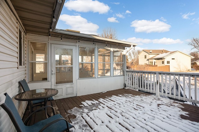 snow covered deck featuring a sunroom