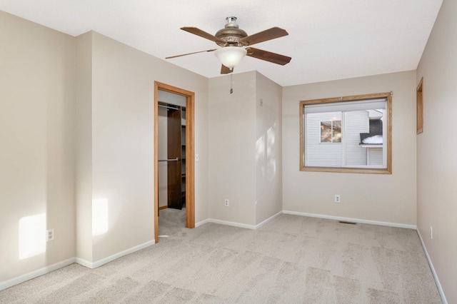 unfurnished room featuring carpet flooring, baseboards, visible vents, and a ceiling fan