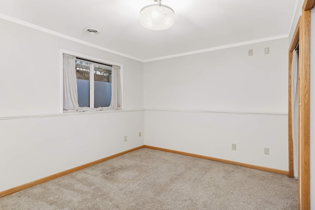 carpeted spare room featuring visible vents, baseboards, and crown molding