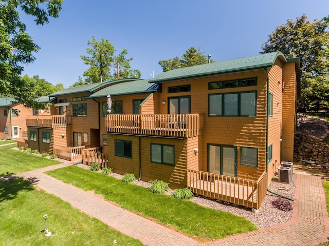 rear view of house featuring a yard, central air condition unit, a balcony, and metal roof