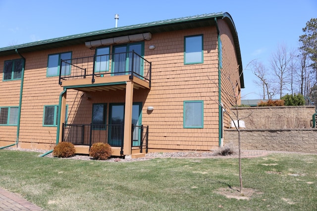 rear view of property featuring a lawn and a balcony