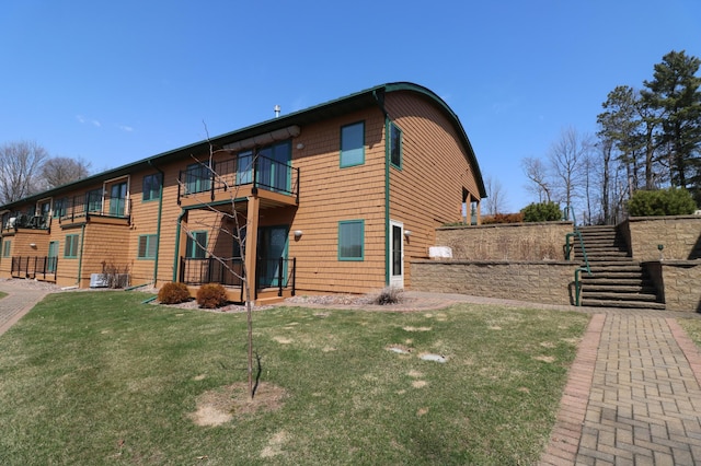 back of house featuring cooling unit, a yard, a balcony, and stairs