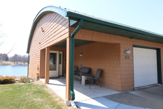exterior space featuring a water view, a patio, and a garage