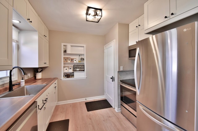 2604 Clearwater Rd, Saint Cloud, MN 56301 - kitchen featuring stainless steel appliances, a sink, light wood finished floors, and white cabinetry