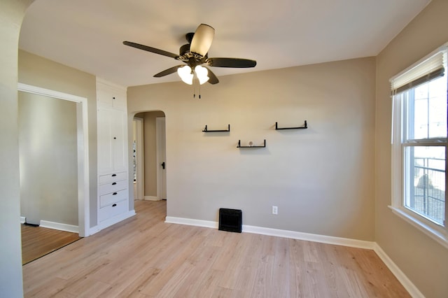 2604 Clearwater Rd, Saint Cloud, MN 56301 - empty room with arched walkways, light wood-style flooring, healthy amount of natural light, and a ceiling fan