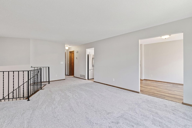 unfurnished room featuring baseboards, light carpet, and visible vents