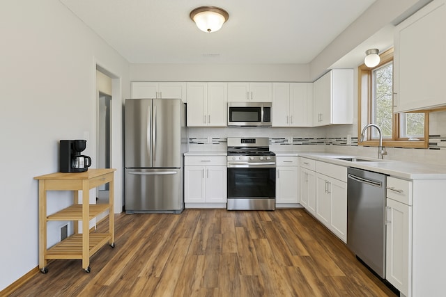kitchen with decorative backsplash, dark wood-style flooring, a sink, light countertops, and stainless steel appliances