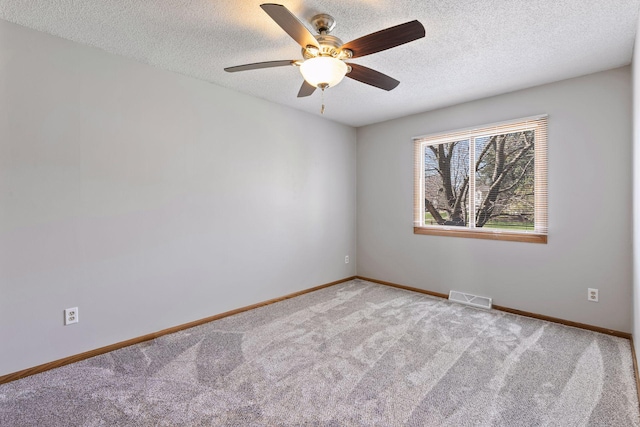 spare room featuring carpet floors, a ceiling fan, a textured ceiling, and visible vents