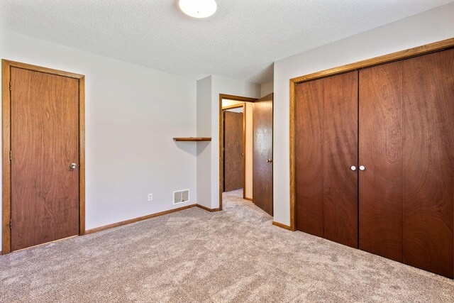 unfurnished bedroom featuring visible vents, carpet flooring, baseboards, and a textured ceiling