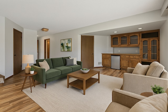 living room featuring visible vents, baseboards, indoor bar, recessed lighting, and light wood finished floors