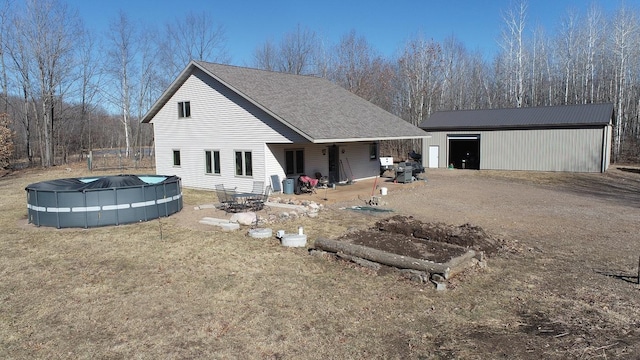 rear view of house with a covered pool, an outdoor structure, and a yard