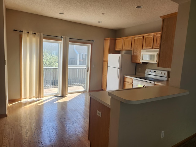 11330 Davenport Cir NE Unit F, Blaine, MN 55449 - kitchen featuring white appliances, a textured ceiling, light countertops, hardwood / wood-style flooring, and a peninsula