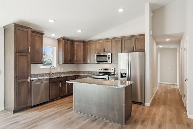 224 9th Ave Ct NW, Lonsdale, MN 55046 - kitchen with light stone counters, a kitchen island, appliances with stainless steel finishes, light wood finished floors, and vaulted ceiling