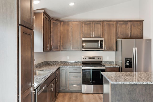 224 9th Ave Ct NW, Lonsdale, MN 55046 - kitchen with lofted ceiling, light wood-style flooring, light stone counters, and appliances with stainless steel finishes