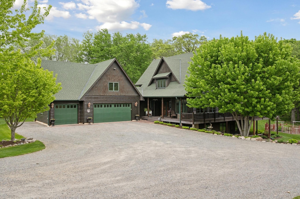 view of front facade featuring a garage, roof with shingles, driveway, and a porch