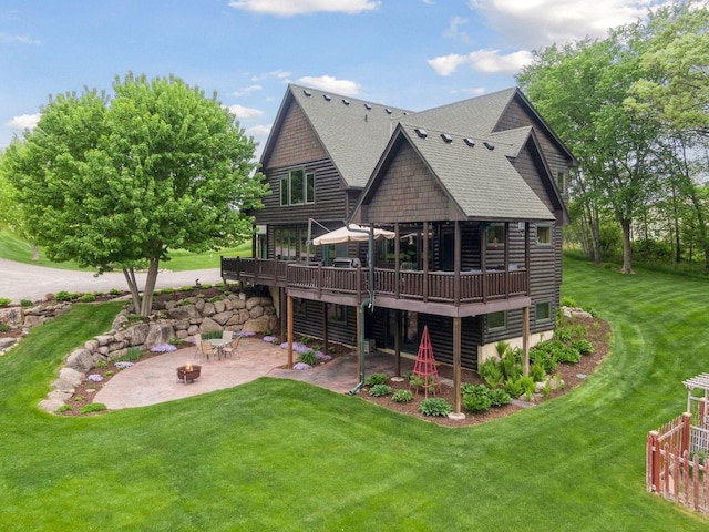 rear view of property featuring a lawn, an outdoor fire pit, and a patio