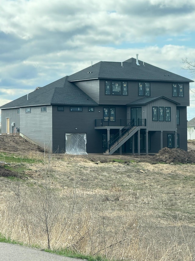 rear view of property with stairway and roof with shingles