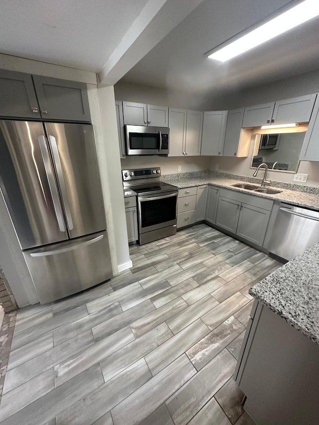 412 Holly Ln, Mankato, MN 56001 - kitchen with light stone countertops, wood tiled floor, gray cabinets, a sink, and appliances with stainless steel finishes