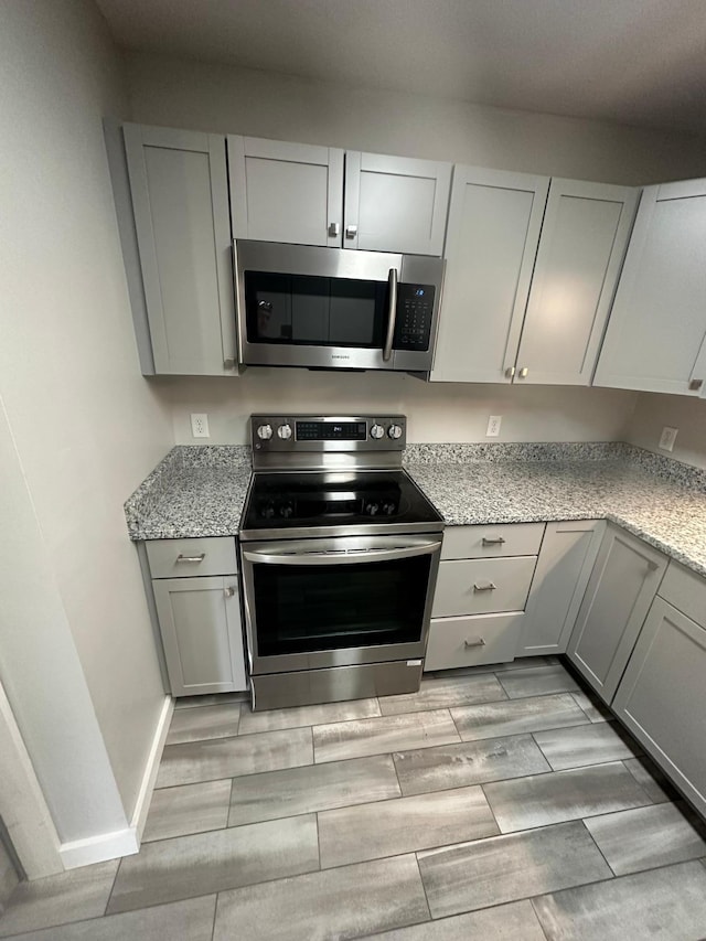 412 Holly Ln, Mankato, MN 56001 - kitchen with light stone counters, gray cabinets, appliances with stainless steel finishes, and wood finish floors