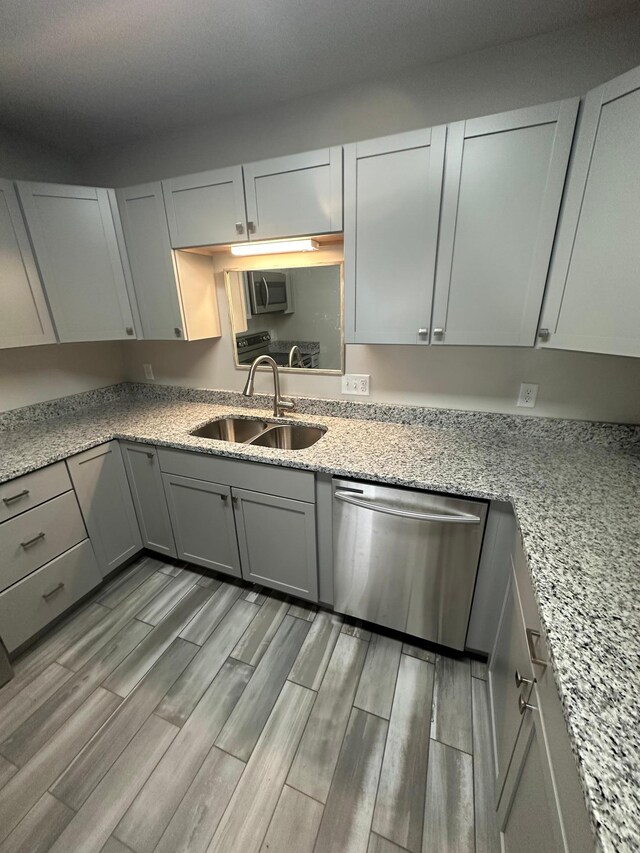 412 Holly Ln, Mankato, MN 56001 - kitchen featuring light stone countertops, wood finish floors, gray cabinetry, a sink, and appliances with stainless steel finishes