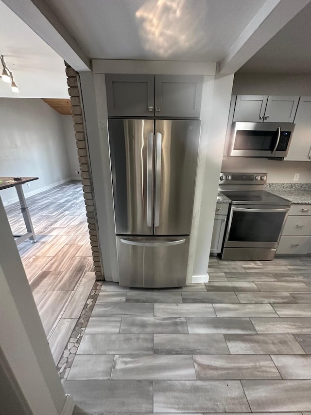 412 Holly Ln, Mankato, MN 56001 - kitchen with wood finish floors, stainless steel appliances, baseboards, and gray cabinetry