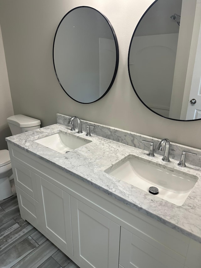 412 Holly Ln, Mankato, MN 56001 - bathroom featuring double vanity, toilet, wood finished floors, and a sink