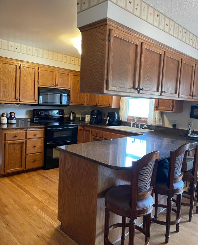 kitchen featuring a sink, brown cabinetry, black appliances, and dark countertops