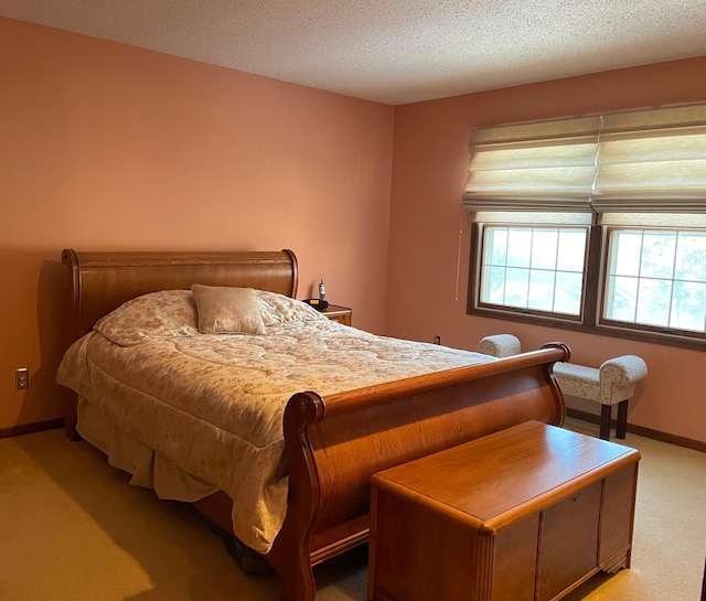 bedroom with light carpet, baseboards, and a textured ceiling