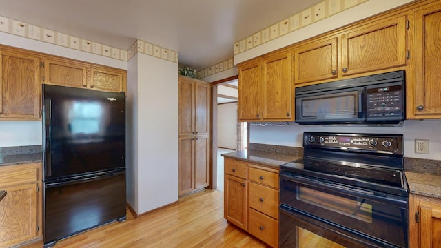 kitchen featuring brown cabinetry, light wood-type flooring, and black appliances