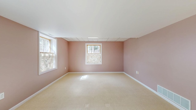 empty room featuring light carpet, baseboards, and visible vents