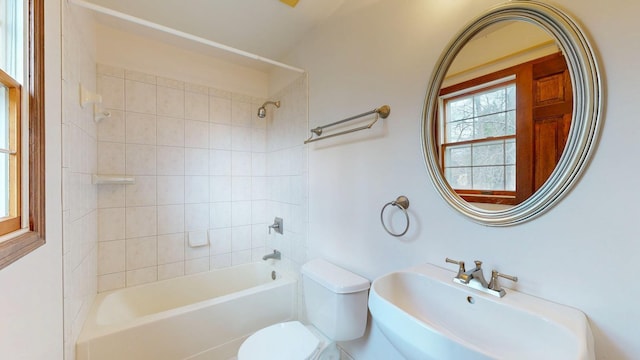 bathroom featuring toilet, tub / shower combination, and a sink