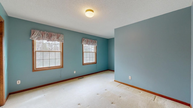 carpeted empty room with visible vents, baseboards, and a textured ceiling