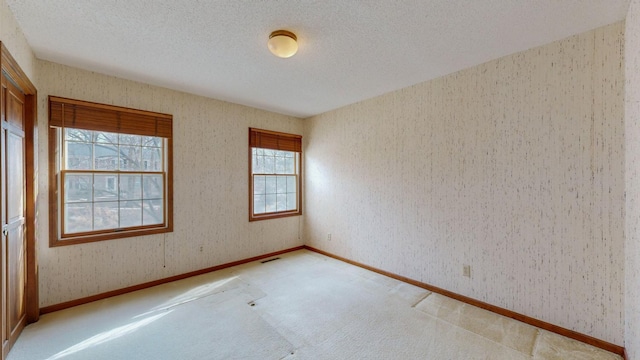 unfurnished room with light carpet, baseboards, visible vents, and a textured ceiling