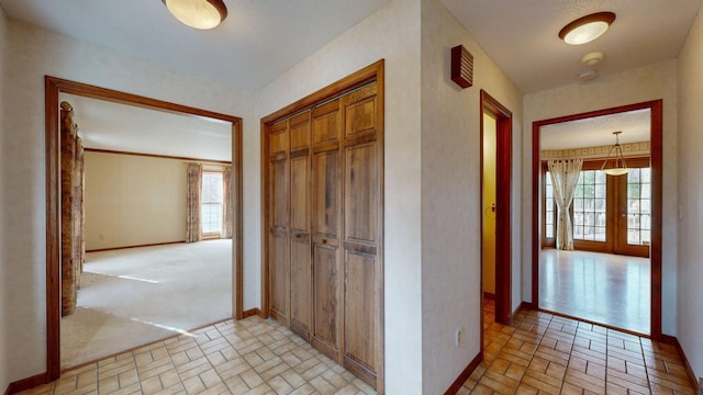 corridor with french doors, baseboards, and brick patterned floor