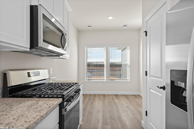 18756 Ivanhoe St NW, Elk River, MN 55330 - kitchen with stainless steel appliances, light wood finished floors, white cabinets, and light stone counters