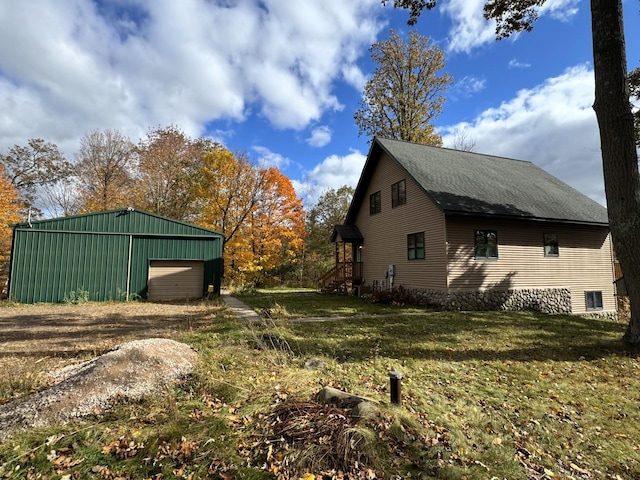 N2641 Cipra Rd, Sarona, WI 54870 - view of home's exterior with a garage, an outdoor structure, dirt driveway, a lawn, and roof with shingles