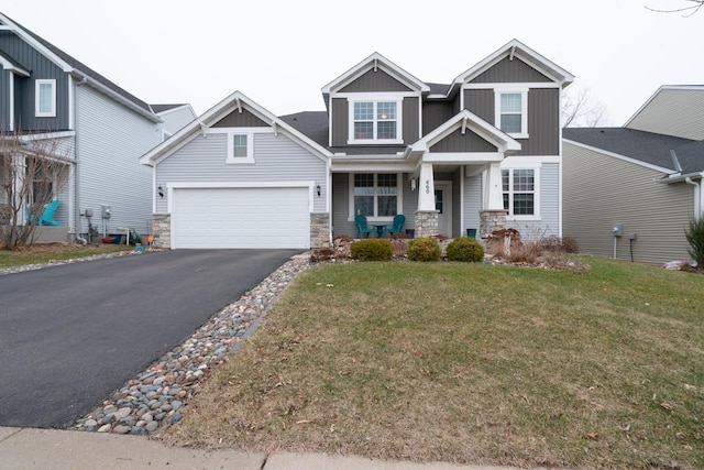460 14th St NW, New Brighton, MN 55112 - craftsman-style home with driveway, covered porch, stone siding, a front lawn, and a garage