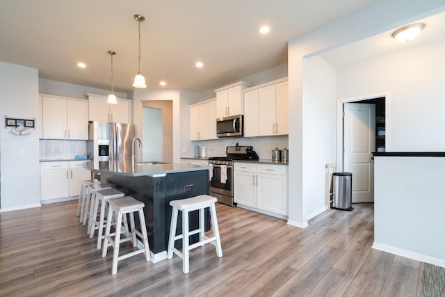 460 14th St NW, New Brighton, MN 55112 - kitchen featuring stainless steel appliances, a sink, tasteful backsplash, a breakfast bar, and light wood-style floors