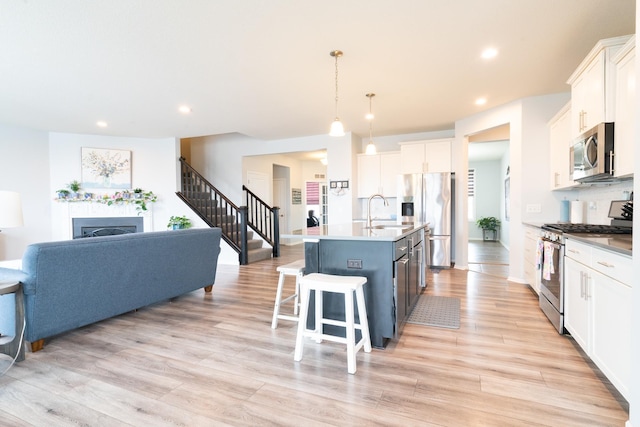 460 14th St NW, New Brighton, MN 55112 - kitchen featuring stainless steel appliances, white cabinets, a center island with sink, light wood-type flooring, and recessed lighting